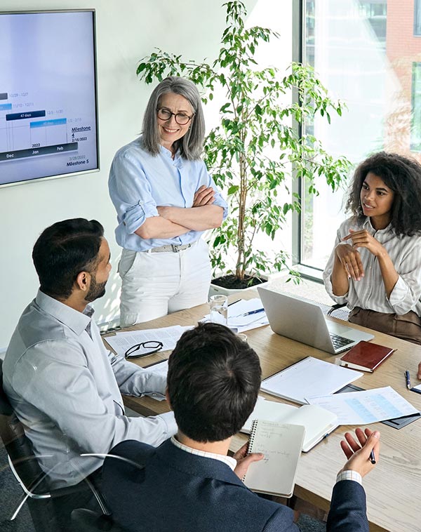 Four colleagues discussing a project around a conference table in a bright office.